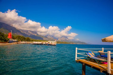 KEMER, TURKEY: Türkiye 'nin Akdeniz kıyısındaki popüler turizm beldesi Kemer' de güneşli bir günde plaj ve dağ manzaralı manzara.