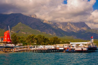 KEMER, TURKEY: Türkiye 'nin Akdeniz kıyısındaki popüler turizm beldesi Kemer' de güneşli bir günde plaj ve dağ manzaralı manzara.