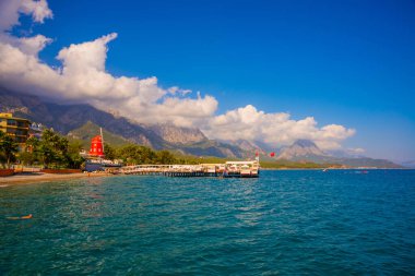 KEMER, TURKEY: Türkiye 'nin Akdeniz kıyısındaki popüler turizm beldesi Kemer' de güneşli bir günde plaj ve dağ manzaralı manzara.