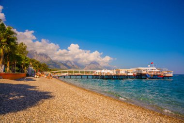 KEMER, TURKEY: Türkiye 'nin Akdeniz kıyısındaki popüler turizm beldesi Kemer' de güneşli bir günde plajda ve dağlarda güzel manzara.