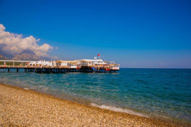KEMER, TURKEY: Türkiye 'nin Akdeniz kıyısındaki popüler turizm beldesi Kemer' de güneşli bir günde plajda ve dağlarda güzel manzara.