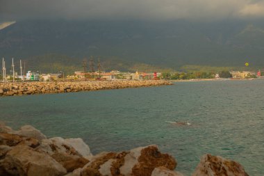 KEMER, TURKEY: Türkiye 'nin Akdeniz kıyısındaki popüler turizm beldesi Kemer' de güneşli bir günde plaj ve mavi deniz manzaralı cennet manzarası.