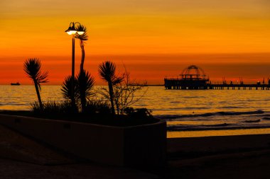 Arnavutluk 'un Durres plajında gün batımına karşı sokak ışıkları silueti oluşturuldu.