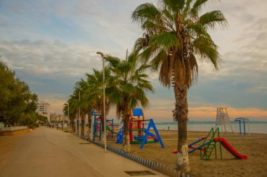 DURRES, ALBANIA: Arnavutluk 'un Durres plajında palmiye ağacı gezinti güvertesi ve mavi deniz.