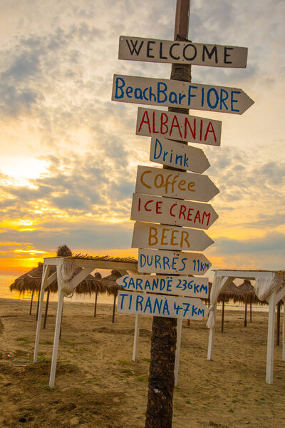 ДУРРЕС, АЛБАНИЯ: Надписи в виде стрелок, знаки на пляже на закате в Дурресе.