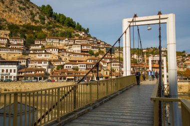 Berat 'ın eski kasabasındaki Osum Nehri üzerindeki yaya köprüsünden geçerek. UNESCO Dünya Mirası Alanı.