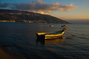 VLORA / VLORE, ALBANIA: Denizdeki günbatımının arka planında botlarla güzel bir akşam manzarası.