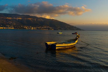 VLORA / VLORE, ALBANIA: Denizdeki günbatımının arka planında botlarla güzel bir akşam manzarası.