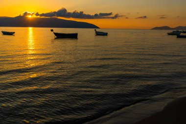 VLORA / VLORE, ALBANIA: Denizde güzel gün batımı, güneşin arka planında balıkçı tekneleri siluetleri.