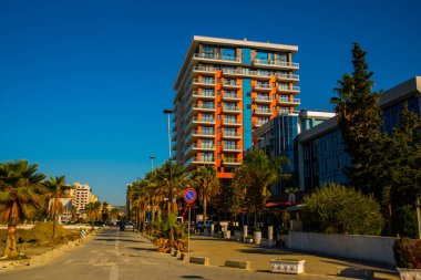 VLORA / VLORE, ALBANIA: Arnavutluk 'un Vlora kentinde yeni çağdaş binalar ve palmiye ağaçlı bir yol.