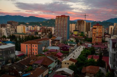 Mavi dağların arka planına karşı gökdelenlerle birlikte gecekondu mahallesi. Yüksek bir binanın penceresinden Batumi şehrinin görüntüsü.