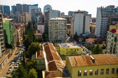 BATUMI, GEORGIA: yüksek bir binanın penceresinden Batumi şehir manzarası. Mavi dağların arka planında gökdelenlerle birlikte gecekondu mahallesi.