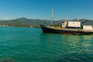 BATUMI, GEORGIA: Georgi 'nin Adjara bölgesinde bir yaz günü rıhtımlara demirlemiş bir yolcu istasyonu ve tekneleri ile Batumi limanının deniz manzarası.