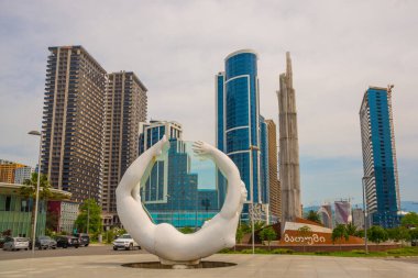 BATUMI, GEORGIA: heykel bileşimi rotasyonu. Cam bir disk üzerinde hareket eden kadın ve erkek heykelleri bütünleşiktir. Batumi 'de alışılmadık gökdelenler.