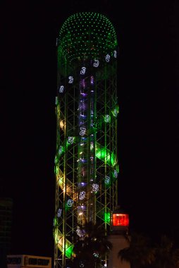 BATUMI, GEORGIA: Alfabetik Kule ile gece manzarası ve Adjara 'nın Batumi bölgesinde aydınlık bir deniz feneri. Kule, Gürcistan alfabesinin benzersizliğini simgeliyor..