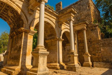 Arka planda mavi gökyüzünde Adrian Gate 'i görüyoruz. Mermer ve kireçtaşından antik yapılar, Antalya, Türkiye.