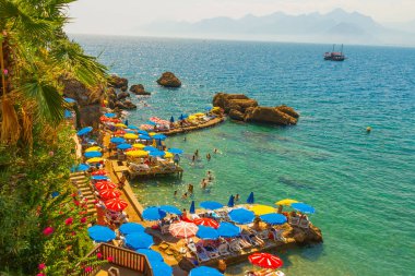 Mermerli sahilinde, Antalya 'nın merkezinde renkli şemsiyeler var. Popüler sahil beldesi Antalya 'nın Kaleici ilçesinde temiz mavi sulara sahip güzel bir sahil..