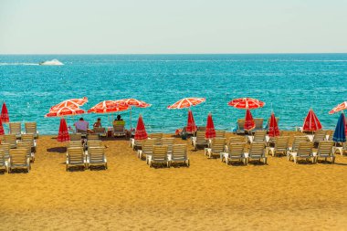 Türkiye 'nin Antalya kentinde güneşli bir yaz gününde Lara plajında güneş pansiyonları ve şemsiyeler.