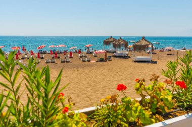 Türkiye 'nin Antalya kentinde güneşli bir yaz gününde, Lara plajında çardaklar, güneşlikler ve şemsiyeler.