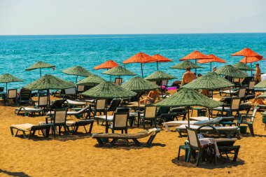 Türkiye 'nin Antalya kentinde güneşli bir yaz gününde Lara plajında güneş pansiyonları ve şemsiyeler.