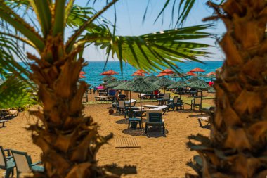 Türkiye 'nin Antalya kentinde güneşli bir yaz gününde Lara plajında güneş pansiyonları ve şemsiyeler.