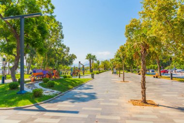Türkiye 'nin Antalya kentinde güneşli yaz mevsiminde Konyaalti plajındaki güzel ağaçlar ve yollar.