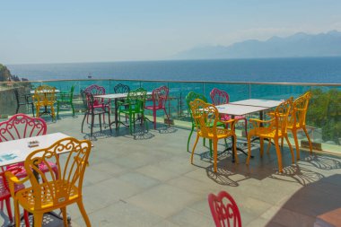 Antalya 'da deniz ve dağ manzaralı renkli sandalyeli bir kafe. Kafenin güzel manzarası, Akdeniz ve Antalya, Türkiye 'deki dağlar.