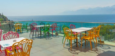 Antalya 'da deniz ve dağ manzaralı renkli sandalyeli bir kafe. Kafenin güzel manzarası, Akdeniz ve Antalya, Türkiye 'deki dağlar.