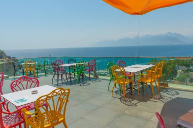 Antalya 'da deniz ve dağ manzaralı renkli sandalyeli bir kafe. Kafenin güzel manzarası, Akdeniz ve Antalya, Türkiye 'deki dağlar.
