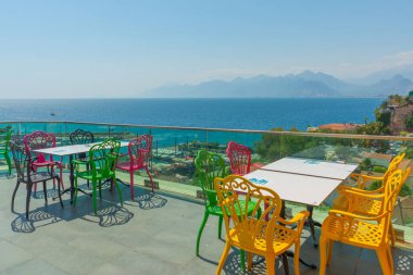 Antalya 'da deniz ve dağ manzaralı renkli sandalyeli bir kafe. Kafenin güzel manzarası, Akdeniz ve Antalya, Türkiye 'deki dağlar.