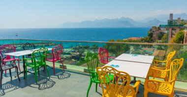 Antalya 'da deniz ve dağ manzaralı renkli sandalyeli bir kafe. Kafenin güzel manzarası, Akdeniz ve Antalya, Türkiye 'deki dağlar.