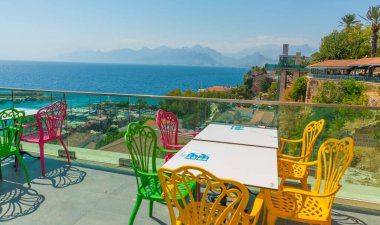 Restoranda deniz manzaralı ve eski kasaba manzaralı renkli sandalyeler var. Kafenin güzel manzarası, Akdeniz ve Antalya, Türkiye 'deki dağlar.