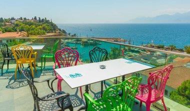 Restoranda deniz manzaralı ve eski kasaba manzaralı renkli sandalyeler var. Kafenin güzel manzarası, Akdeniz ve Antalya, Türkiye 'deki dağlar.