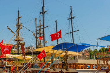 Mavi gökyüzü ve denizin arka planında, korsan olarak süslenmiş bir eğlence gemisi yelkenlisi. Gemi, Antalya limanından turistleri kıyı şeridi etrafında bir geziye çıkarıyor..