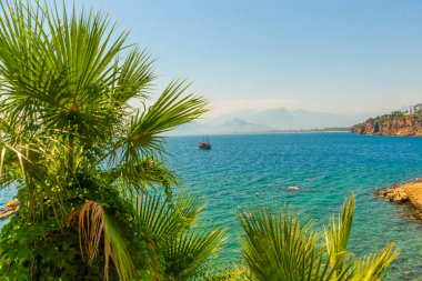 Türkiye 'nin Antalya kentinde güneşli bir yaz gününde Akdeniz kıyısında turistlerle dolu güzel bir gemi yelken açıyor.