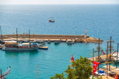 Antalya Antalya 'daki eski limanda deniz feneri ve güneşli bir yaz gününde gemi ve teknelerle liman, Türkiye.