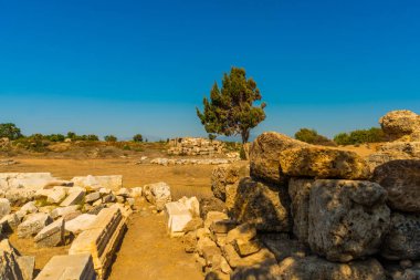 Eski harabeler ve güneşli bir yaz gününde, Kenar mahallesinde mavi bir gökyüzünün arka planına karşı bir yol. Yana, Antalya ili, Türkiye.