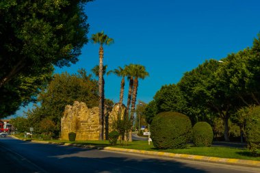 Eski harabeler ve güneşli bir yaz gününde, Kenar mahallesinde mavi bir gökyüzünün arka planına karşı bir yol. Yana, Antalya ili, Türkiye.