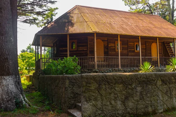 KOBULETI, GEORGIA: Houten orthodoxe kerk in een schaduwrijk park op een zonnige zomerdag. — Stockfoto