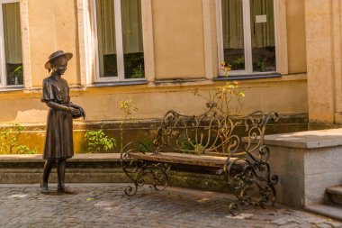 KUTAISI, GEORGIA: Kraliyet Mahallesi Kutaisi 'nin tarihi merkezinde bir bankın yanında şapkalı bir kızın metal heykeli.