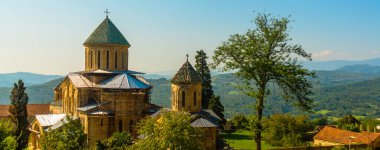KUTAISI, GEORGIA, IMERETI: Mavi gökyüzünün arka planında güneşli bir yaz gününde Gelati Manastırı manzaralı manzara. UNESCO tarafından korunuyor..