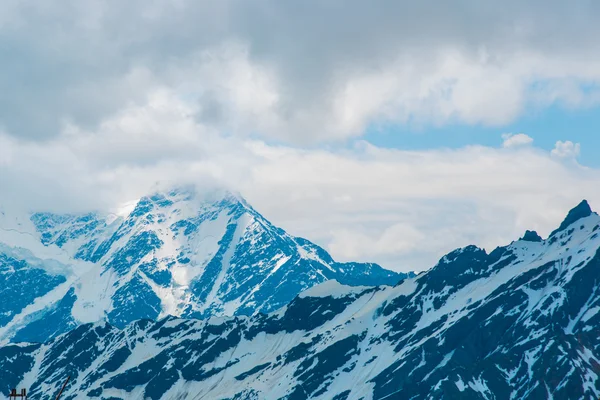 Mavi gökyüzünde bulutlar karşı dağlarda kar. Elbrus bölge. Kafkasya. — Stok fotoğraf