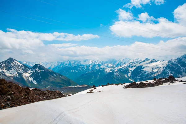 Snö på bergen mot den blå himlen i molnen. Elbrus regionen. Kaukasus. — Stockfoto