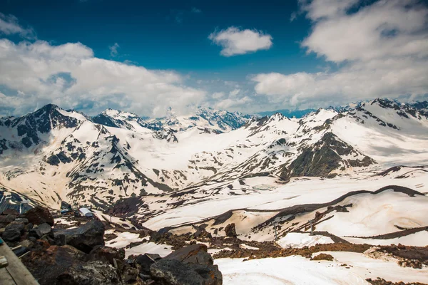 Snow on the mountains against the blue sky in the clouds.The Elbrus region.The Caucasus. — Stock Photo, Image