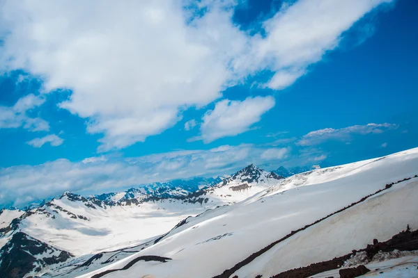 Neve sulle montagne contro il cielo blu nelle nuvole.La regione dell'Elbrus. . — Foto Stock