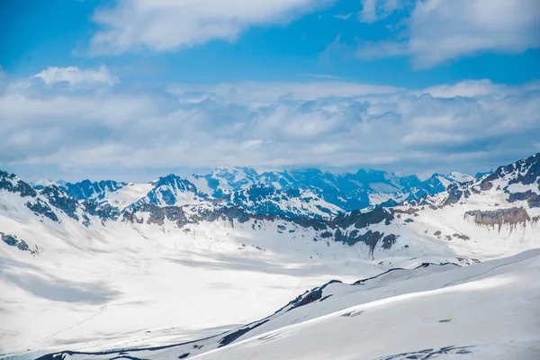 Neige sur les montagnes contre le ciel bleu dans les nuages.La région d'Elbrus Le Caucase . — Photo