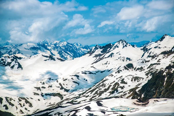 Neige sur les montagnes contre le ciel bleu dans les nuages.La région d'Elbrus Le Caucase . — Photo