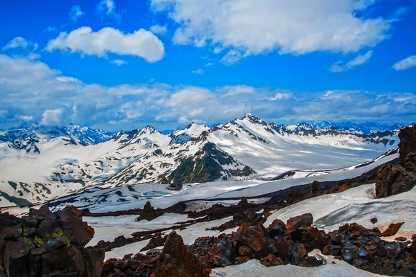 Neve sulle montagne contro il cielo blu nelle nuvole.La regione dell'Elbrus. . — Foto Stock