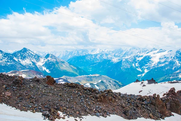 Snö på bergen mot den blå himlen i molnen. Elbrus regionen. Kaukasus. — Stockfoto