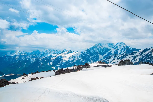 Sneeuw op de bergen tegen de blauwe hemel in de wolken. De Elbroes regio. De Kaukasus. — Stockfoto